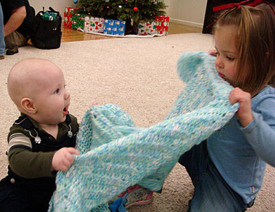 James and Kasey, sitting on the floor at Ellis Truss, Kasey trying to put her younger cousin to bed